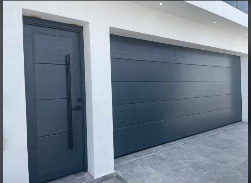 Puerta Seccional Gris Oxford con Puerta Peatonal de Jaladera Vertical Negra